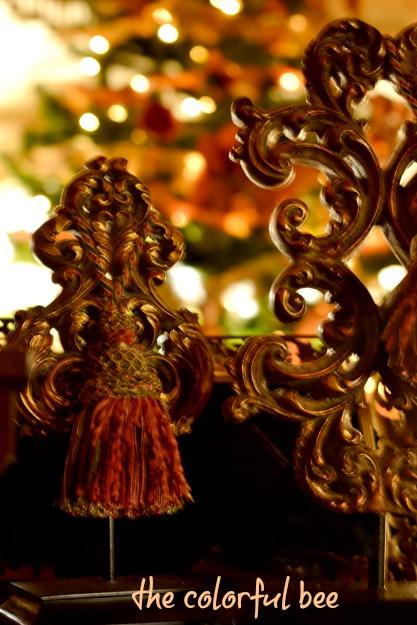 Putting Christmas Away scrolled acanthus ornaments with Christmas tree and lights in background