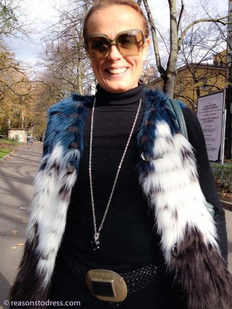 A stylish woman mom walking in Modena, Italy wearing a blue white and black faux fur vest gilet by London brand urban code