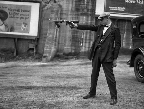 Truth vs. Fiction: The Bank-Robbing Style of Warren Oates as Dillinger In this 1927 photograph, Lt. Oscar Bayer of the LAPD Detective Bureau aims a Thompson with a removed stock (and no magazine) for demonstration purposes. The Dillinger gang modified their Thompsons this way, but as this photo pre-dated Dillinger's spree by six years, they were clearly not the first to do so.