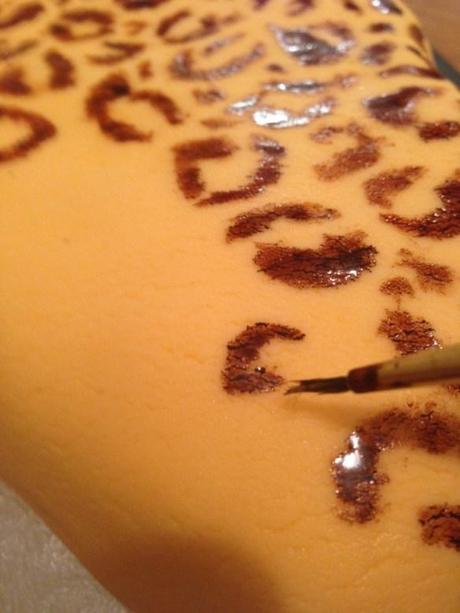 hand painting leopard print spots dark brown onto cake using food colouring