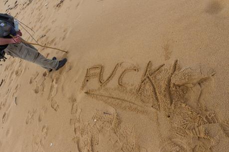word fuck written in sand on beach