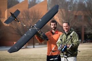 Wake Forest biology graduate student Max Messinger and biology professor Miles Silman pose with their remote controlled helicopter and fixed-wing aircraft on Davis Field