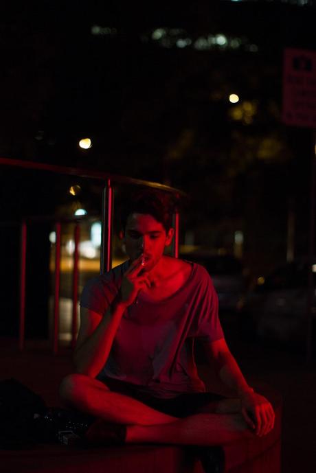 Under the red light at night man smoking at night under red light