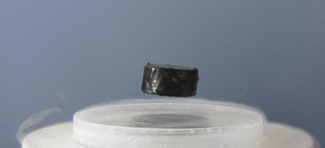 A levitating magnet floats above a superconducting surface.