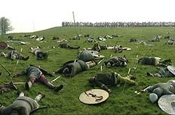Shows a photograph of a drama reconstruction of the bloody aftermath of the battle. There are bodies strewn across the field, many with arrows in them.