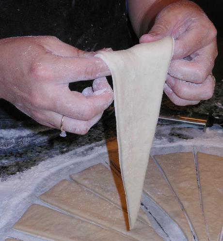 It's super easy to make a fancy crescent shape.  Jenna (I just LOVE her!) showed me this trick.  Pick up one of your triangular shaped pieces of dough.  Rest the wide side of the triangle on your two index fingers.  Then flip the dough in a circular motion around your fingers.