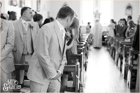 Groom looks down the aisle waiting for bride at yorkshire wedding