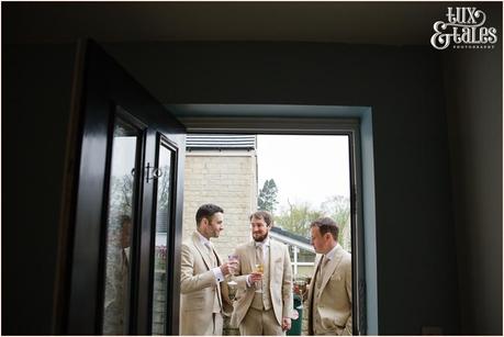 Groomsmen stand outside framed by door in Yorkshire wedding