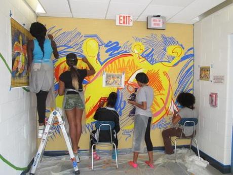 Students painting bright mural in a hallway