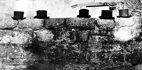 wedding blog photograph of top hats on a stone wall