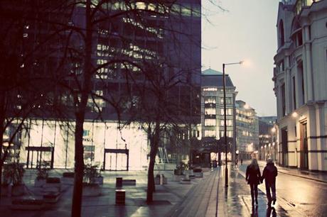 As night falls, our couple watch the city lights twinkle into life