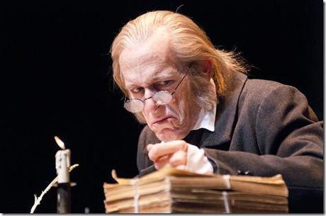 Ebenezer Scrooge (Larry Yando) pours over paperwork at his desk on Christmas Eve in the Goodman Theatre’s 34th annual production of A Christmas Carol. 