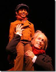 Tiny Tim (Roni Akurati) proclaims, “God bless us everyone!” on the shoulders of Ebenezer Scrooge (Larry Yando), in the 34th annual production of Goodman Theatre’s A Christmas Carol. 