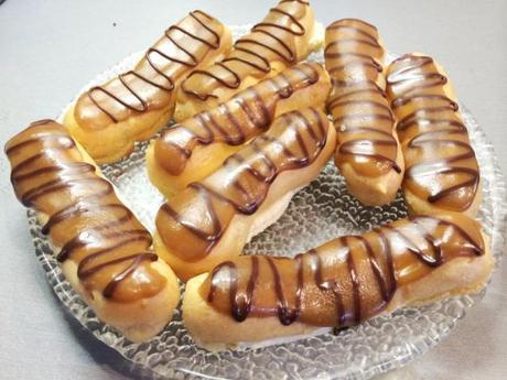 homemade caramel choux pastry eclairs filled with whipped cream decorated with piped chocolate
