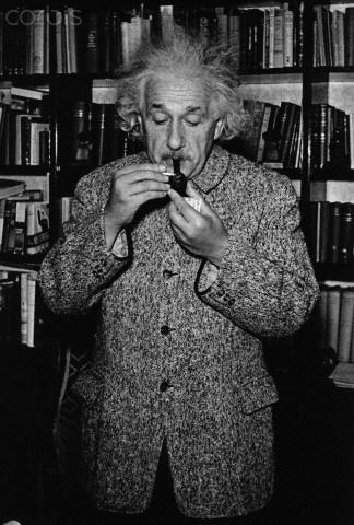 1940, Princeton, New Jersey, USA --- Albert Einstein, dressed in a warm tweed overcoat, lights his pipe in his home study. --- Image by © Lucien Aigner/CORBIS