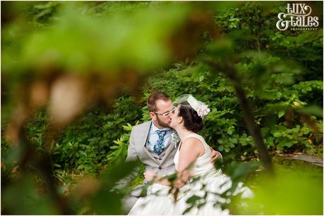 Lake District Wedding Photographer | Derwentwater Youth Hostel Wedding | Alternative eclectic wedding styling | Tux & Tales Photography | Bride & Groom Portraits in the Woods Near Waterfall | Kissing
