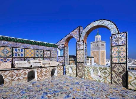 Brightly coloured tiles in blue, yellow and green cover the interior of an open-roofed mosque building in Tunisia.
