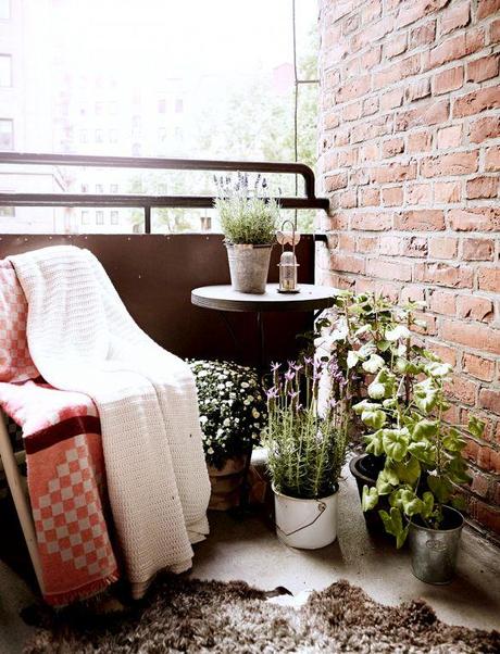 Inside a Chic Small Home With Major Style | DomaineHome.com // Cozy balcony space with plants, seating, and blankets.