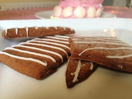 chocolate and ginger biscuits decorated with white chocolate lines leaning cake in background