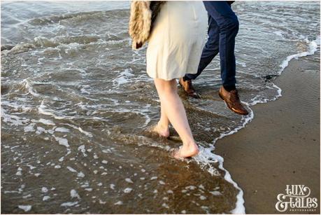 Photography Engagement Shoot in Whitby | Girl wearing Red Flower crown | Alterntive Couple whereing Vintage clothing | walking in water at beach