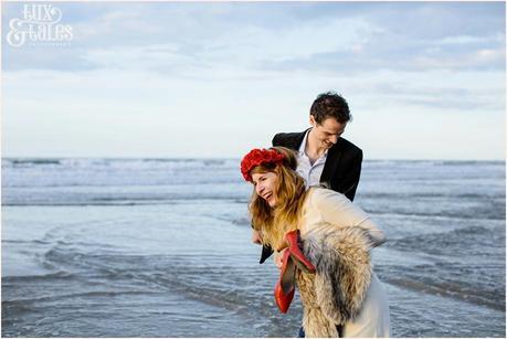 Photography Engagement Shoot in Whitby | Girl wearing Red Flower crown | Alterntive Couple whereing Vintage clothing | Couple laughing at beach