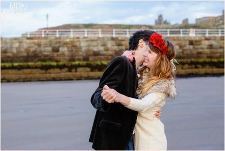 Photography Engagement Shoot in Whitby | Girl wearing Red Flower crown | Alterntive Couple whereing Vintage clothing | Hugging with whitby abbey in the background