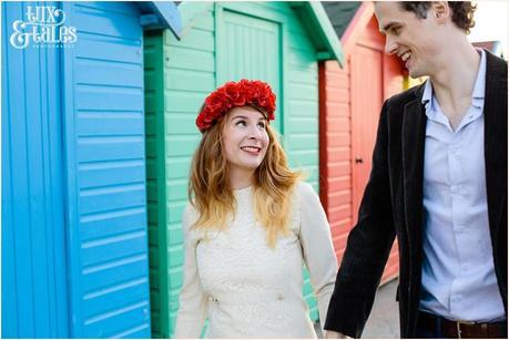Photography Engagement Shoot in Whitby | Girl wearing Red Flower crown | Alterntive Couple whereing Vintage clothing | Rainbow coloured beach huts