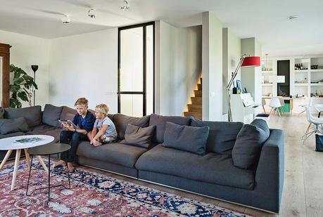 Amsterdam canal house living room with cocoon sofa, persian rug and illuminated stairway