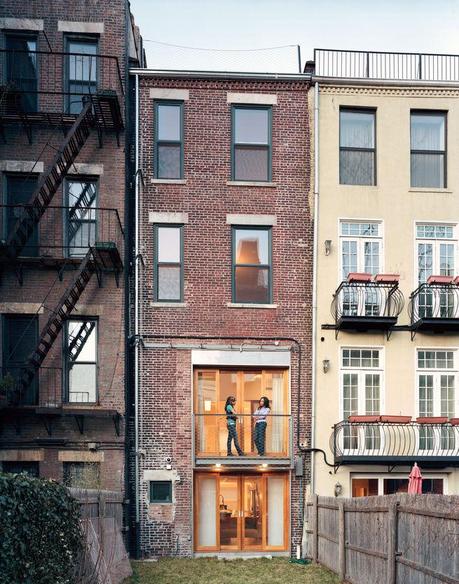 A second-story balcony overlooks a small yard.