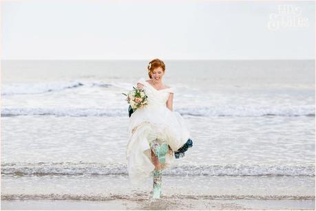 Bride & Groom Portraits in the rain at Newton Hall beachside wedding photography | Bride kicking up water in wellies