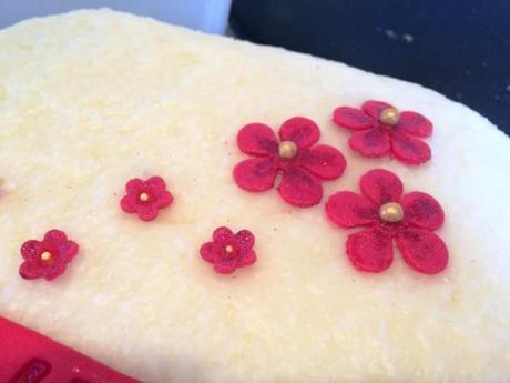 red fondant festive flowers on coconut iced cake decorated with edible glitter