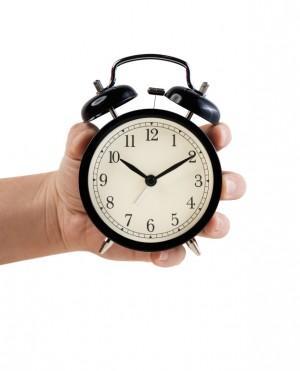 Hand holding Retro style alarm clock, isolated on white