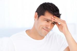 Worried man having a headache sitting in his bedroom