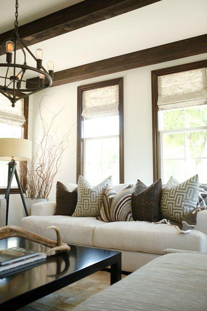 Cozy and neutral living room with white walls, exposed wood beams, and wood trim.