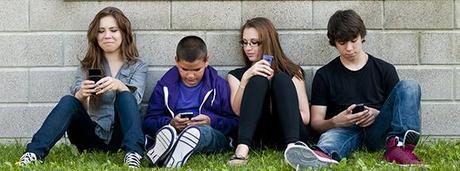 group of teenagers sitting outdoors and using cellphone