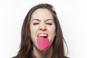 Angry girl biting a paper heart