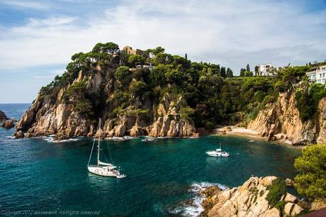 Two white pleasure boats afloat along the rocky Costa Brava coastline, Spain