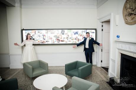 Bride and Groom in front of panel of their pictures