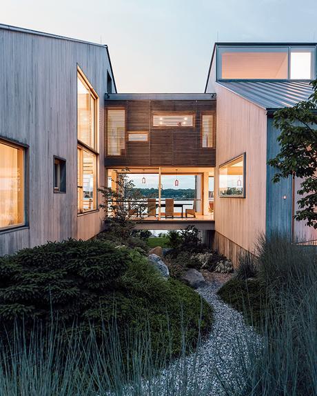 Modern Connecticut summer home renovation with bleached cedar siding on the volumes connected by glass bridge