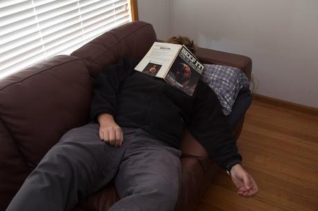 lying on couch with book over face