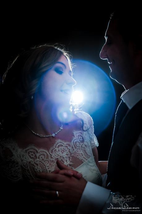 Bride and groom dance with light behind