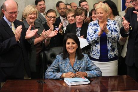 Surrounded by advocates and lawmakers in the Statehouse lobby, Gov. Nikki Haley on Thursday signs the domestic violence bill stiffening penalties, barring offenders from possessing guns and requiring education.