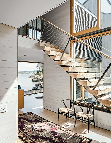 Modern Connecticut summer home renovation with white cedar paneling, glass windows by Town & Country Glass in the entry and ash risers on the stairs