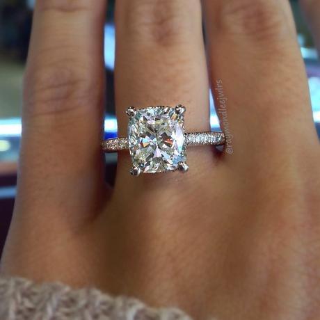 Cushion Cut solitaire engagement ring on thin diamond band.