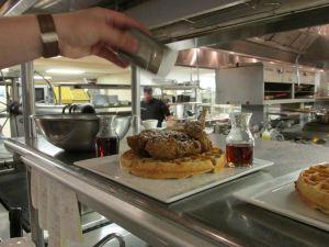 Chef Kelley Schmidt puts the finishing touches on an order of chicken & waffles.