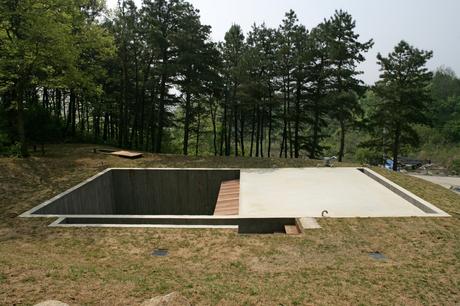 A square hole in the ground and a concrete slab are all that demarcate Byoung Cho’s Earth House from the surrounding countryside. 