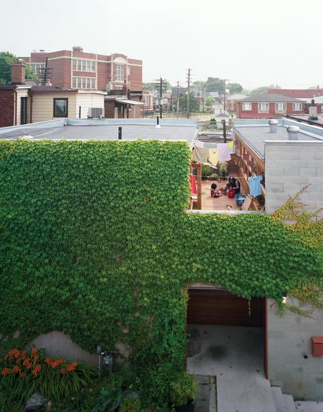 A wide cut across the top of the structure made room for a second-floor courtyard where the family can catch some sun but maintain their privacy. On the ground level, the front door is tucked into an ivy-covered alcove lined with ipe, a material used thro