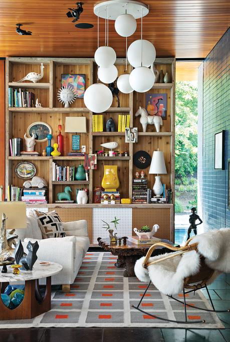 wood shelves of various sizes ornament the back wall, white couches, and a wood coffee table sit on a red, white and gray carpet 