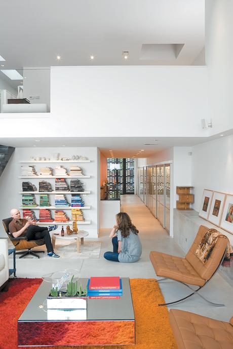 Hernandez and Surratt relax in the living room, which is enlivened by the house’s internal topography. A short flight of steps divides the interconnected areas and offers a place to sit. Above is a loft that can be converted to a bedroom.