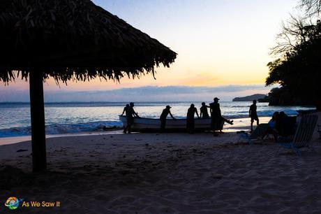 With the sun setting on the beach, locals secure the boats for the night.